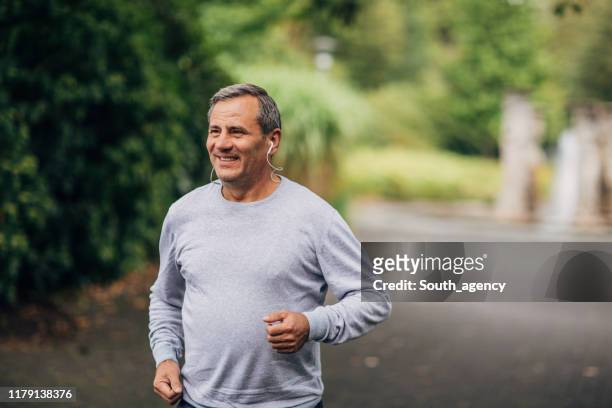 man jogging in park - mature men stock pictures, royalty-free photos & images