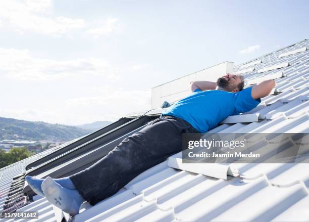 adult man resting on top of house roof - leaf on roof stock-fotos und bilder