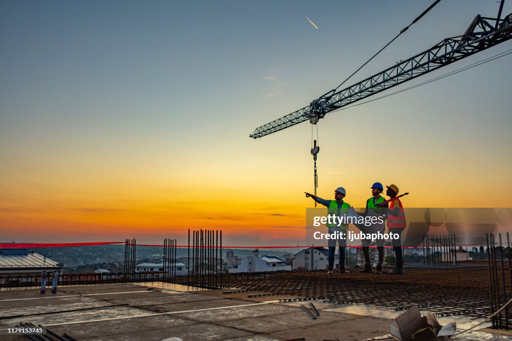 Multi ethic workers talking at construction site reviewing plans