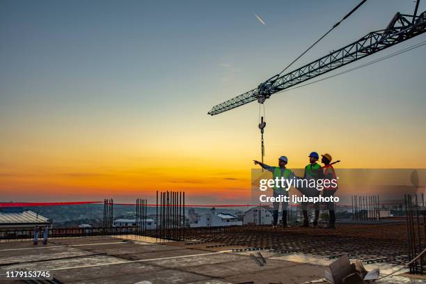 multi ethic workers talking at construction site reviewing plans - business finance and industry photos stock pictures, royalty-free photos & images