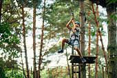 Little boy ziplining in forest
