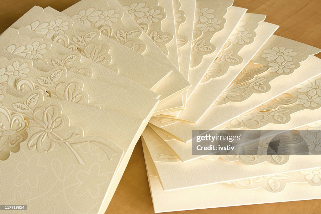 Close-up of white invitation cards with engraved flowers