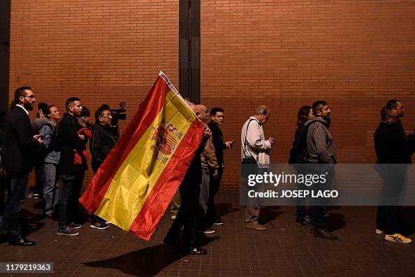 Spanish Queue A supporter holds a Spanish flag as people queue prior to the rally ...