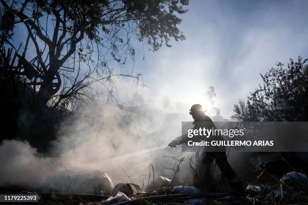 Firefighter works to extinguish a fire affecting two houses on a hillside at Camino Verde neighborhood in Tijuana, Baja California state, Mexico, on...