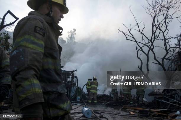 Firefighters work to extinguish a fire affecting two houses on a hillside at Camino Verde neighborhood in Tijuana, Baja California state, Mexico, on...