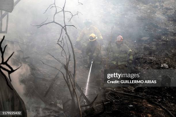 Firefighters work to extinguish a fire affecting two houses on a hillside at Camino Verde neighborhood in Tijuana, Baja California state, Mexico, on...