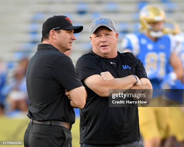 Head coach Chip Kelly of the UCLA Bruins and head coach Jonathan Smith of the Oregon State Beavers talk on the field as their teams warm up before...