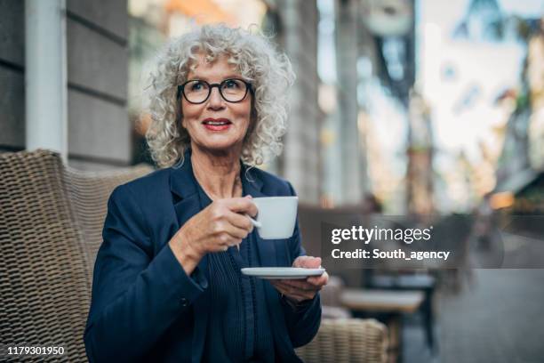 beautiful senior woman drinking a hot drink - senior women cafe stock pictures, royalty-free photos & images