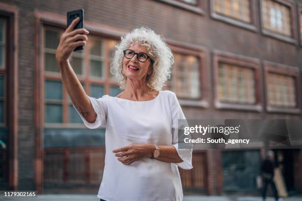 senior woman in the city taking selfie - self portrait photography stock pictures, royalty-free photos & images