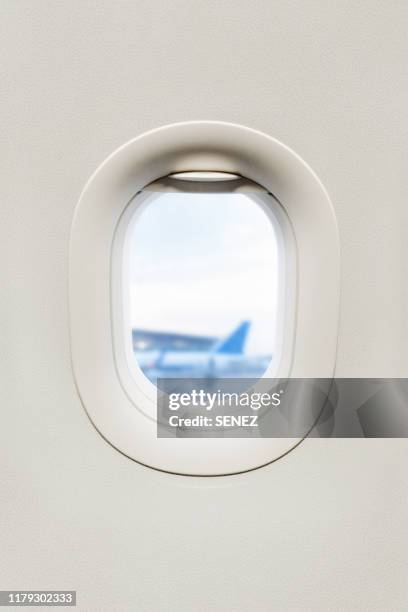 view from inside of plane through airplane window at wing - plane window stock pictures, royalty-free photos & images