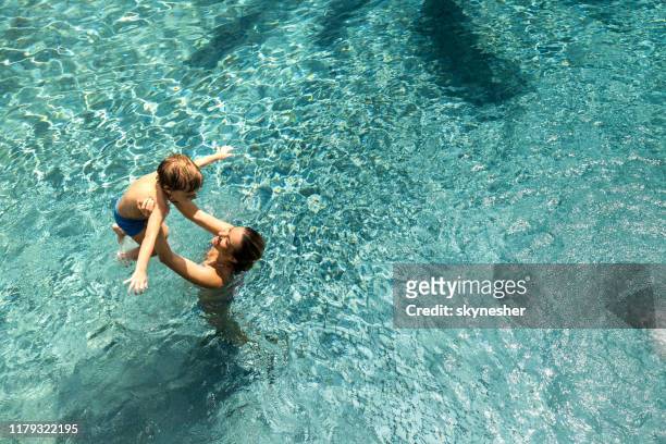 über blick auf glückliche alleinerziehende mutter und ihren sohn spaß im pool. - kids fun indonesia stock-fotos und bilder