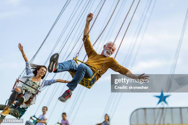zorgeloze mensen met plezier op de ketting swing ride in pretpark. - zweefmolen stockfoto's en -beelden