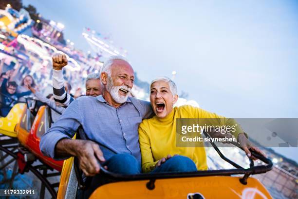 anziani spensierati che si divertono sulle montagne russe al parco divertimenti. - anziani attivi foto e immagini stock