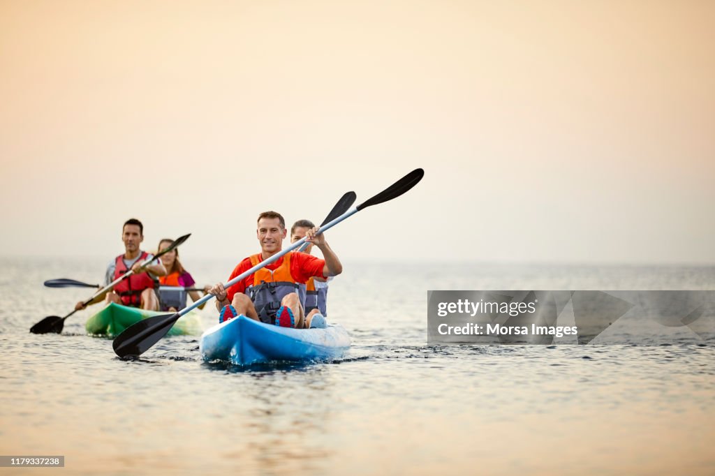 Couples kayaking on river during summer sunset