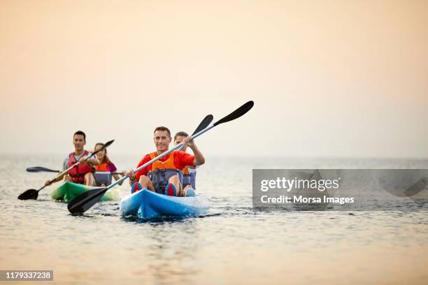 couples kayaking on river during summer sunset - ocean kayak stock pictures, royalty-free photos & images