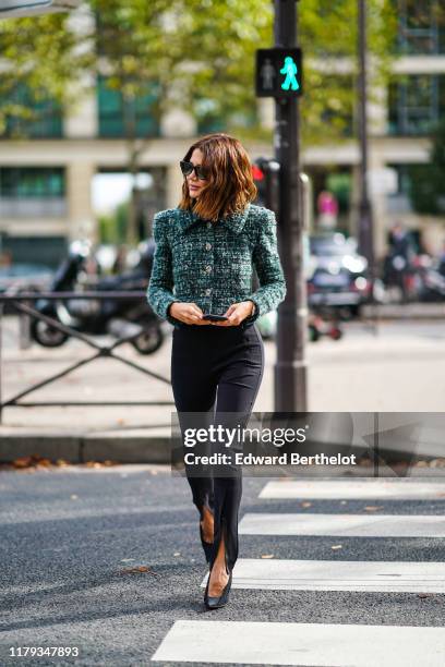 Christine Centenera wears sunglasses, a green tweed jacket with buttons and shoulder pads, black pants, shoes, outside Miu Miu, during Paris Fashion...