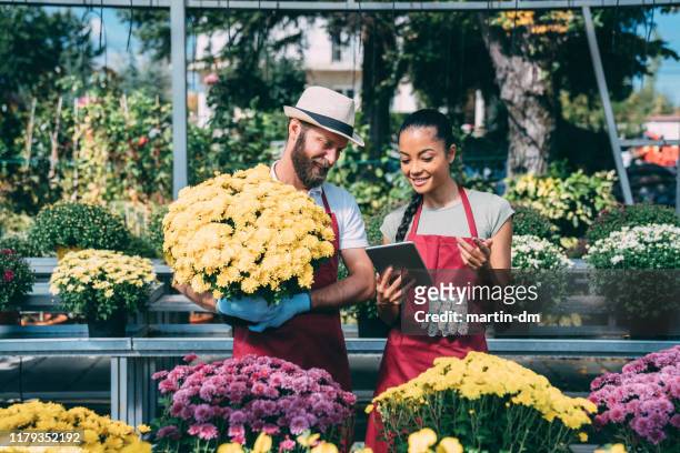 florists working in own family garden center - flower stall stock pictures, royalty-free photos & images