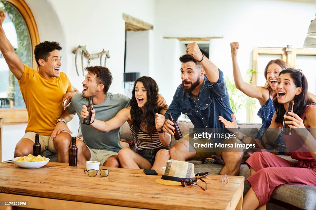 Aficionados jóvenes emocionados celebrando mientras ven la televisión