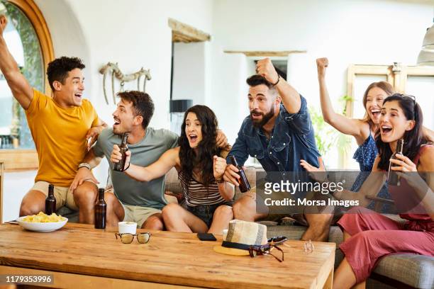 aficionados jóvenes emocionados celebrando mientras ven la televisión - match sport fotografías e imágenes de stock