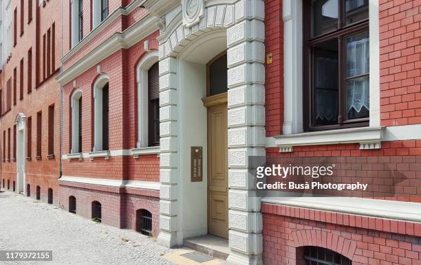 entrance of red brick residential building in the pappelallee / buchholzer strasse street, in the district of prenzlauer berg in the east side of berlin, germany - apartment front door foto e immagini stock
