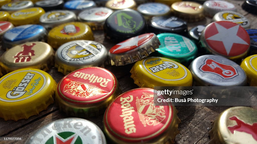 Bottle caps of drinks (mostly beer) on wooden table