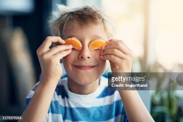 portret van een grappig jongetje dat oranje eet - child eating a fruit stockfoto's en -beelden
