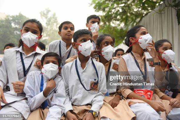 Students wear anti-pollution masks after receiving them from Delhi Chief Minister Arvind Kejriwal during an event, at Rajkiya Pratibha Vikas...