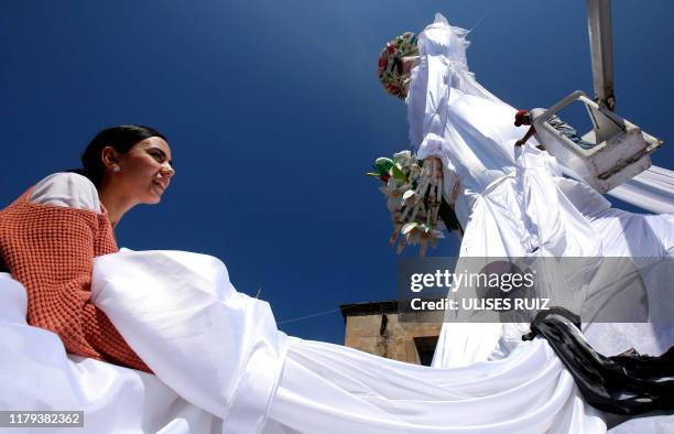 Man and a woman set up a 20-meter-high "Catrina" figure -the biggest in the world-, dressed up as a bride, and the "Catrin", her groom, in the main...