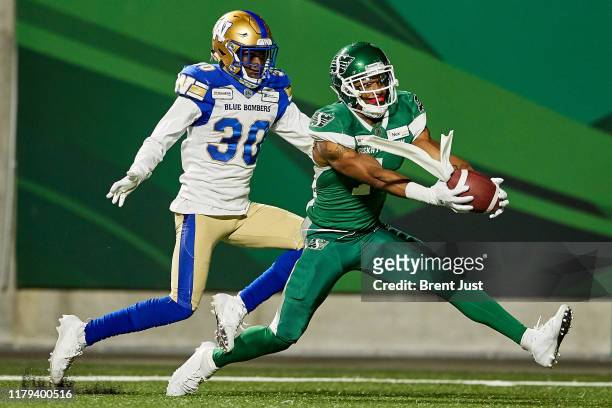 Shaq Evans of the Saskatchewan Roughriders makes a catch behind Winston Rose of the Winnipeg Blue Bombers in the game between the Winnipeg Blue...