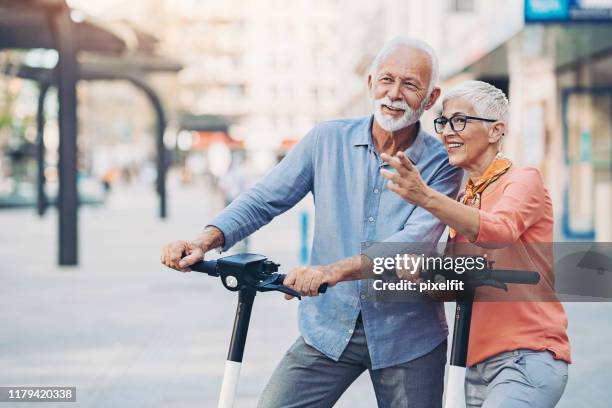 senior couple with e-scooters - couple pointing imagens e fotografias de stock