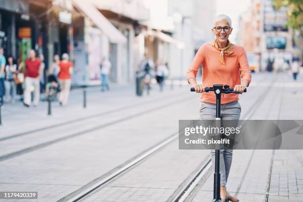 lächelnde seniorin mit einem e-scooter - roller stock-fotos und bilder