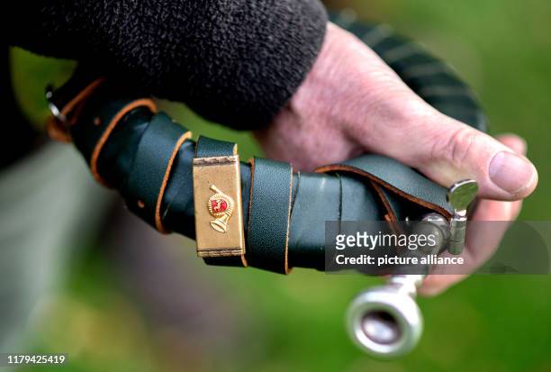 October 2019, Lower Saxony, Liebenau: A participant of a hunt holds his hunting horn with a coat of arms from Lower Saxony in his hands. With the...