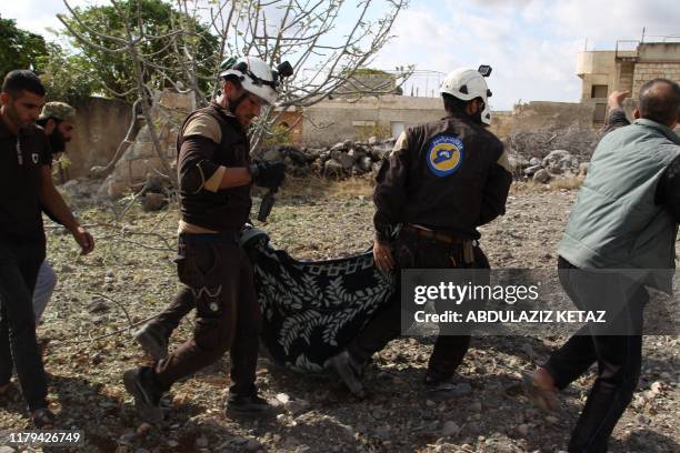 Members of the Syrian Civil Defence carry away one of the victims of a Russian airstrike that hit the village of Jaballa in the south of the Idlib...