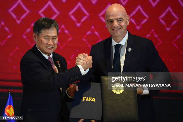 President Gianni Infantino and Association of Southeast Asian Nations Secretary General Lim Jock Hoi shake hands as they pose following a signing...