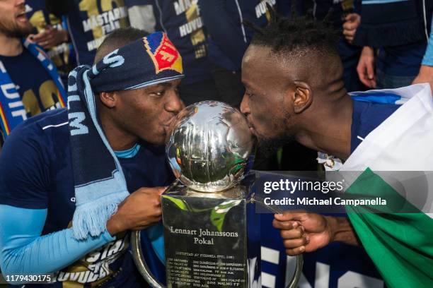 Edward Chilufya and Buya Turay of Djurgardens IF kiss the Lennart Johansson trophy after Djurgardens IF wins the 2019 Allsvenskan season during an...