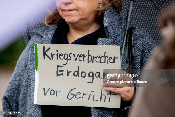 November 2019, Berlin: "War criminal Erdogan on trial" stands on a sign held by a participant at the initial rally of a Kurdish demonstration against...