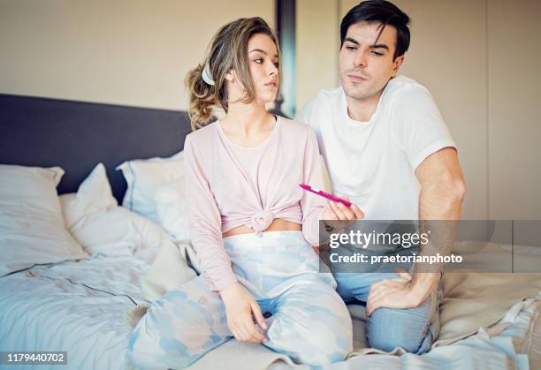 shocked couple is looking positive pregnancy test in the bedroom - human fertility stock pictures, royalty-free photos & images