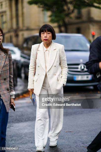 Angelica Cheung, Vogue China Editor-in-Chief, wears a white blazer jacket, a white shirt, a tie, flare pants, white sneakers, outside Miu Miu, during...