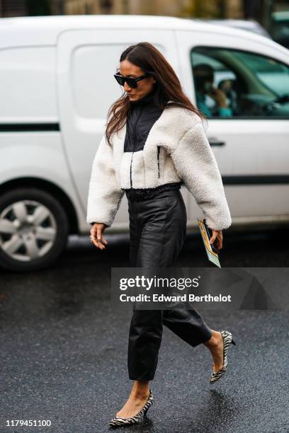 Guest wears sunglasses, a white sheep wool coat, black leather pants, zebra pattern printed shoes, outside Miu Miu, during Paris Fashion Week -...