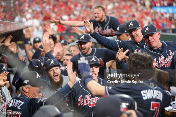 Dansby Swanson of the Atlanta Braves is congratulated by his teammates in the dugout after hitting an RBI double and scoring a run during the ninth...