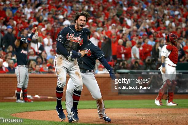 Dansby Swanson of the Atlanta Braves celebrates after scoring a run against the St. Louis Cardinals during the ninth inning in game three of the...