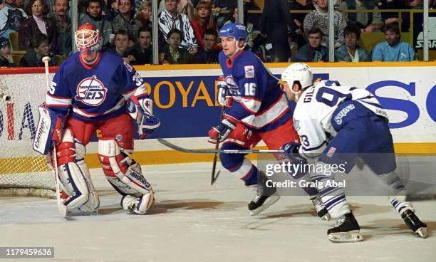 Nikolai Khabibulin and Ed Olczyk of the Winnipeg Jets skate against Doug Gilmour of the Toronto Maple Leafs during NHL game action on November 18,...