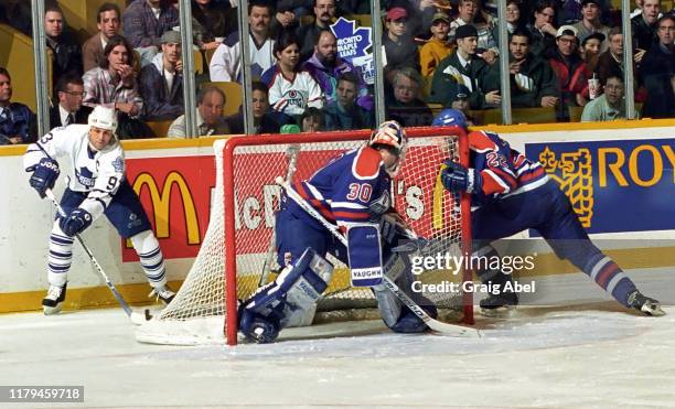 Bill Ranford and Luke Richardson of the Edmonton Oilers skate against Doug Gilmour of the Toronto Maple Leafs during NHL game action on December 23,...