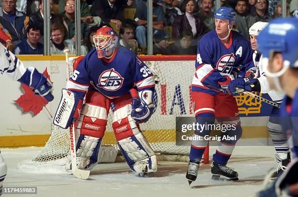 Nikolai Khabibulin and Dave Manson of the Winnipeg Jets skate against Tie Domi of the Toronto Maple Leafs during NHL game action on November 18, 1995...