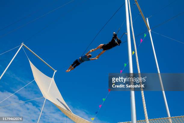 due artisti trapezio che volano nel cielo blu - trapezista foto e immagini stock