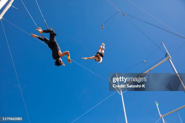 trapeze artists flying in the blue sky - trapeze artist stock pictures, royalty-free photos & images