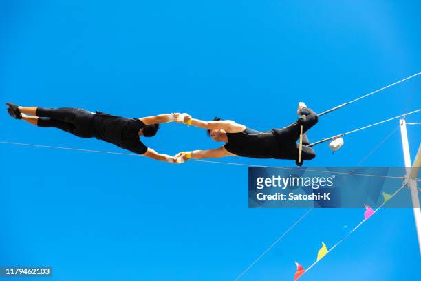 two trapeze artists flying together in the sky - trust stock pictures, royalty-free photos & images