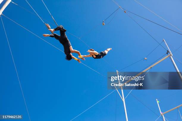 trapezkünstler fliegen am blauen himmel - trapez stock-fotos und bilder