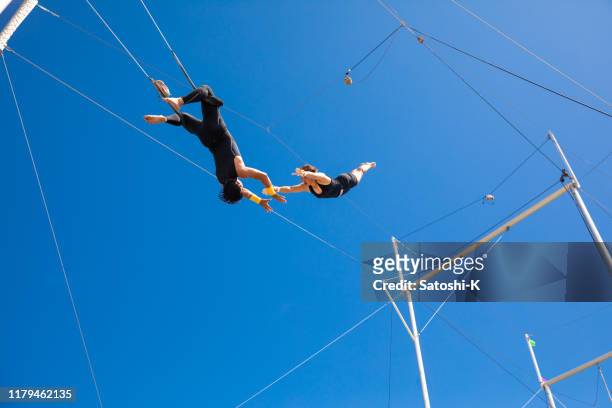 trapeze artists flying in the blue sky - trust stock pictures, royalty-free photos & images