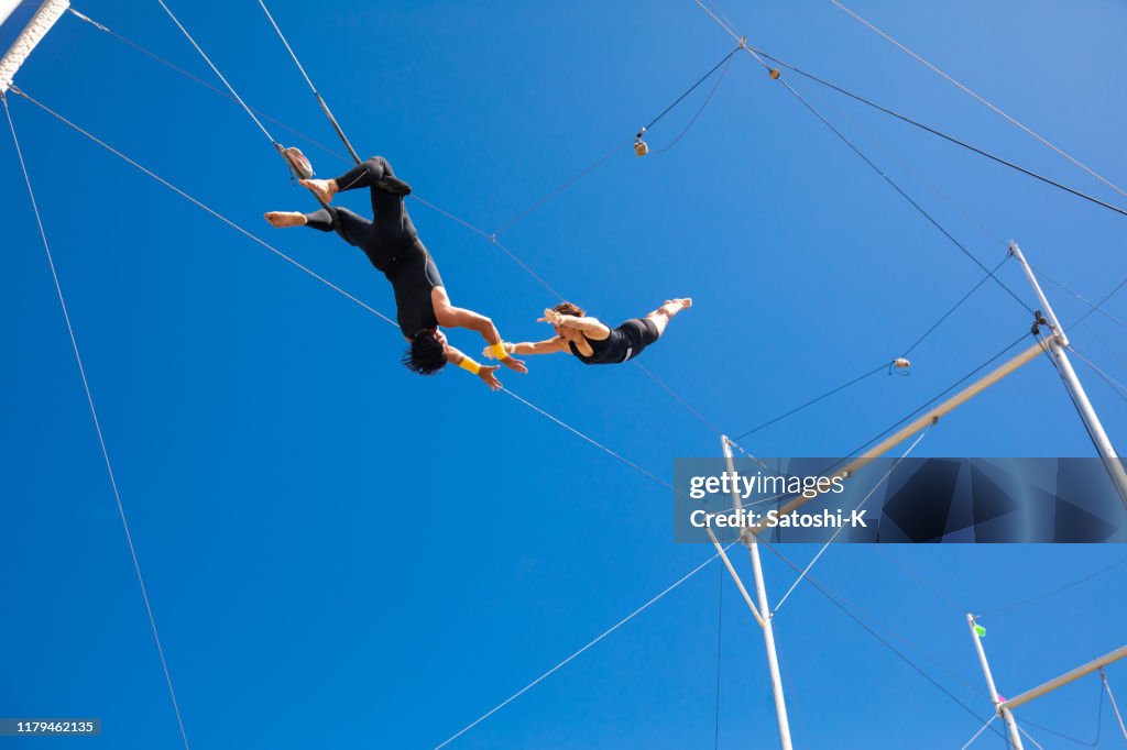 Trapeze konstnärer som flyger i den blå himlen